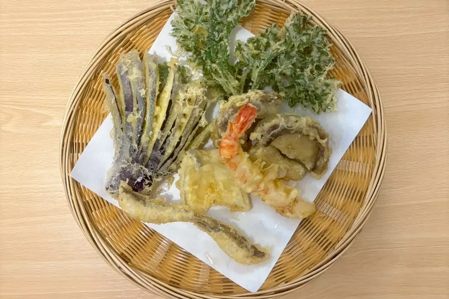 籠に盛られた天ぷらの盛り合わせ。なす、春菊、海老、椎茸、旬の魚